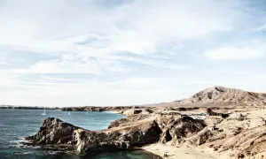 Surowe krajobrazy wulkaniczne Lanzarote, gdzie skutki braku zapasu wody są widoczne na trasach turystycznych, kontrastują z błękitem oceanu i białymi żaglami.