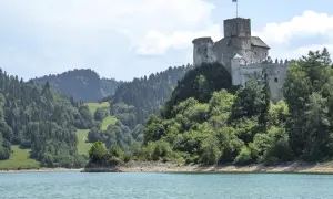 Zamek w Czorsztynie góruje nad jeziorem, otoczony zielonymi wzgórzami i lasami.
