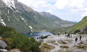 Tatrzański Park Narodowy: ile kosztuje wejście? Widok na Morskie Oko, otoczone górami i lasami, z turystami podziwiającymi krajobraz.