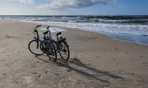 Dwa rowery na piaszczystej plaży nad Bałtykiem. Idealne, by jak zaplanować trasę rowerową wzdłuż polskiego wybrzeża etapami.