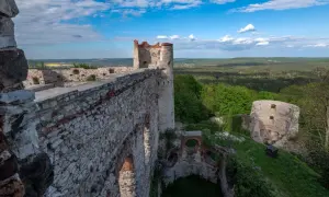 Ruiny zamku Tenczyn w Rudnie, z kamiennymi murami i wieżą, górują nad zielonym krajobrazem.