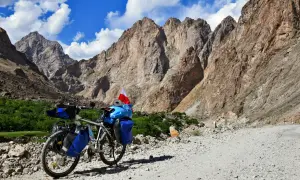 Rower z sakwami i polską flagą na tle gór Pamiru. To inspiracja, jak zaplanować logistykę wyprawy rowerowej przez Pamir Highway.