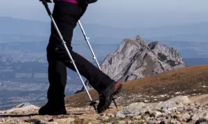 Osoba z kijami do nordic walking na górskim szlaku. Czy warto korzystać z kijów do nordic walking na trasach górskich? Pomagają w stabilizacji i odciążają stawy.