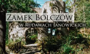 Kamienne ruiny zamku Bolczów w Rudawach Janowickich, porośnięte zielenią, z łukowym wejściem i drewnianym mostkiem.