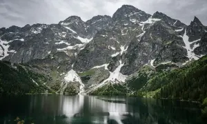 Majestatyczne Tatry nad Morskim Okiem. Trasa widokowa zachwyca skalistymi szczytami, zielonymi lasami i odbijającą się w tafli jeziora naturą.