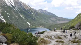 Tatrzański Park Narodowy: ile kosztuje wejście? Widok na Morskie Oko, otoczone górami i lasami, z turystami podziwiającymi krajobraz.