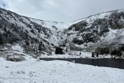Zimowy krajobraz Karkonoszy z jeziorem i ośnieżonymi zboczami. Śnieg i oblodzenie to przyczyny zamykania szlaków w Karkonoskim Parku Narodowym zimą.