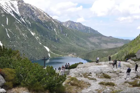 Tatrzański Park Narodowy: ile kosztuje wejście? Widok na Morskie Oko, otoczone górami i lasami, z turystami podziwiającymi krajobraz.