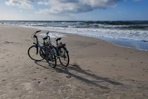 Dwa rowery na piaszczystej plaży nad Bałtykiem. Idealne, by jak zaplanować trasę rowerową wzdłuż polskiego wybrzeża etapami.