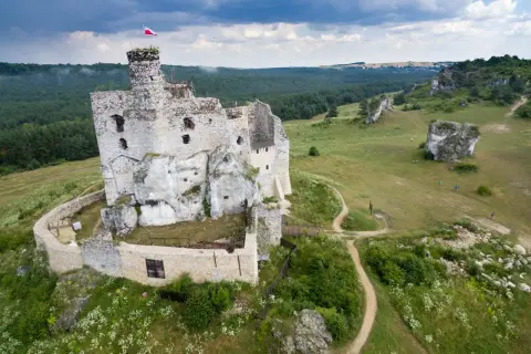 Ruiny zamku w Mirowie, majestatycznie wznoszące się na skale, otoczone zielenią i wapiennymi ostańcami.