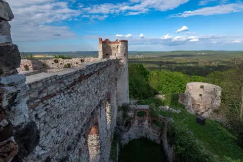 Ruiny zamku Tenczyn w Rudnie, z kamiennymi murami i wieżą, górują nad zielonym krajobrazem.