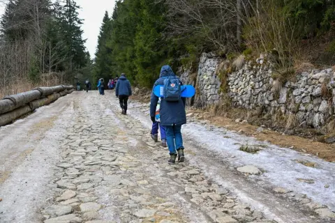 Ludzie idą kamienistą drogą przez las. Wiosenne topnienie śniegu i lodu może być jedną z przyczyn zamykania szlaków turystycznych w parkach narodowych.