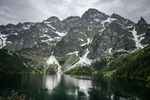 Majestatyczne Tatry nad Morskim Okiem. Trasa widokowa zachwyca skalistymi szczytami, zielonymi lasami i odbijającą się w tafli jeziora naturą.