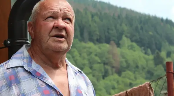 Starszy mężczyzna z zaniepokojoną miną, być może doświadczający objawów przeciążenia serca u osób starszych na szlakach górskich.
