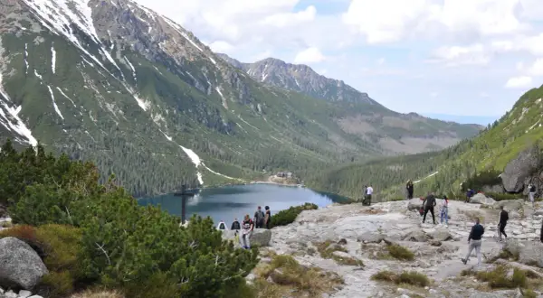 Tatrzański Park Narodowy: ile kosztuje wejście? Widok na Morskie Oko, otoczone górami i lasami, z turystami podziwiającymi krajobraz.