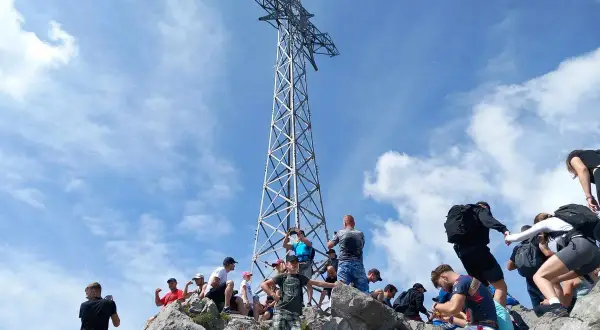 Turyści pod krzyżem na Giewoncie. Zastanawiasz się, ile waży krzyż na Giewoncie? To imponująca konstrukcja!