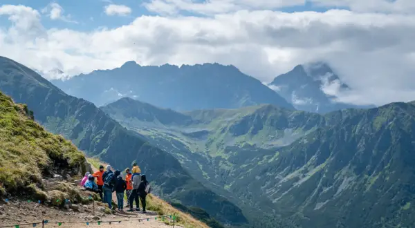 Grupa turystów na szlaku podziwia panoramę Tatr. Czy z Kasprowego widać Rysy? Tak, przy dobrej widoczności można dostrzec ich zarys.