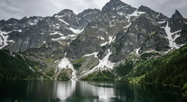 Majestatyczne Tatry nad Morskim Okiem. Trasa widokowa zachwyca skalistymi szczytami, zielonymi lasami i odbijającą się w tafli jeziora naturą.