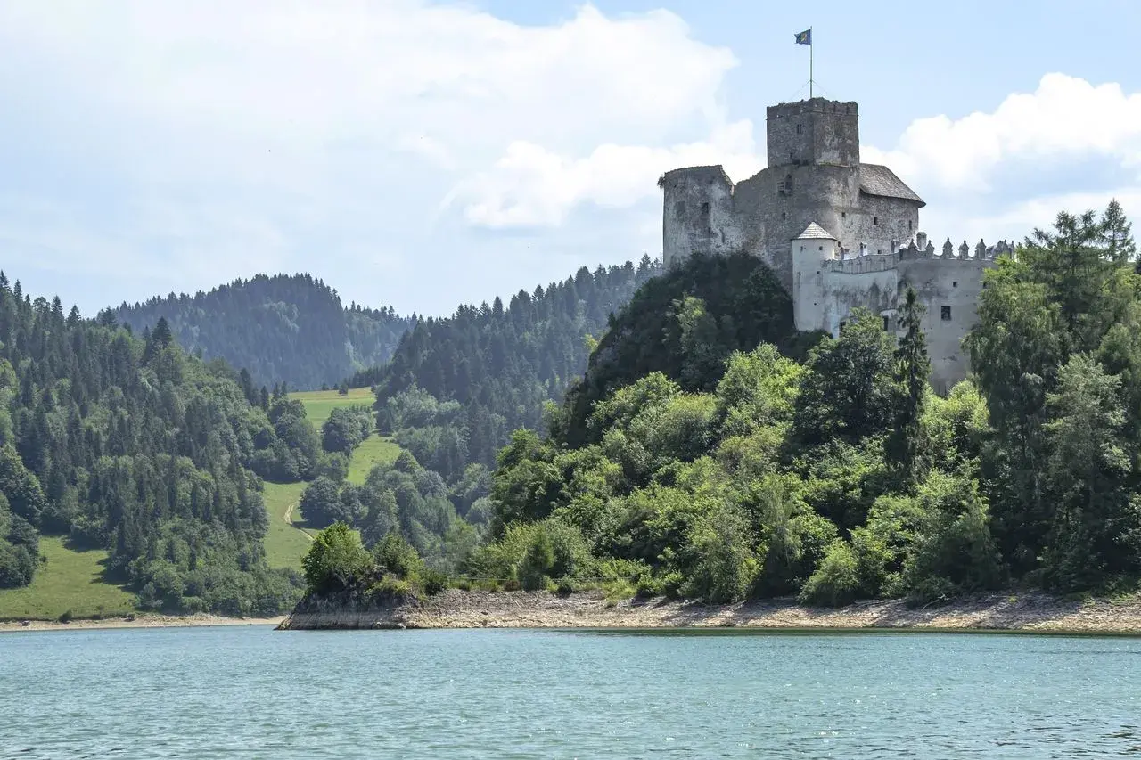 Zamek w Czorsztynie góruje nad jeziorem, otoczony zielonymi wzgórzami i lasami.