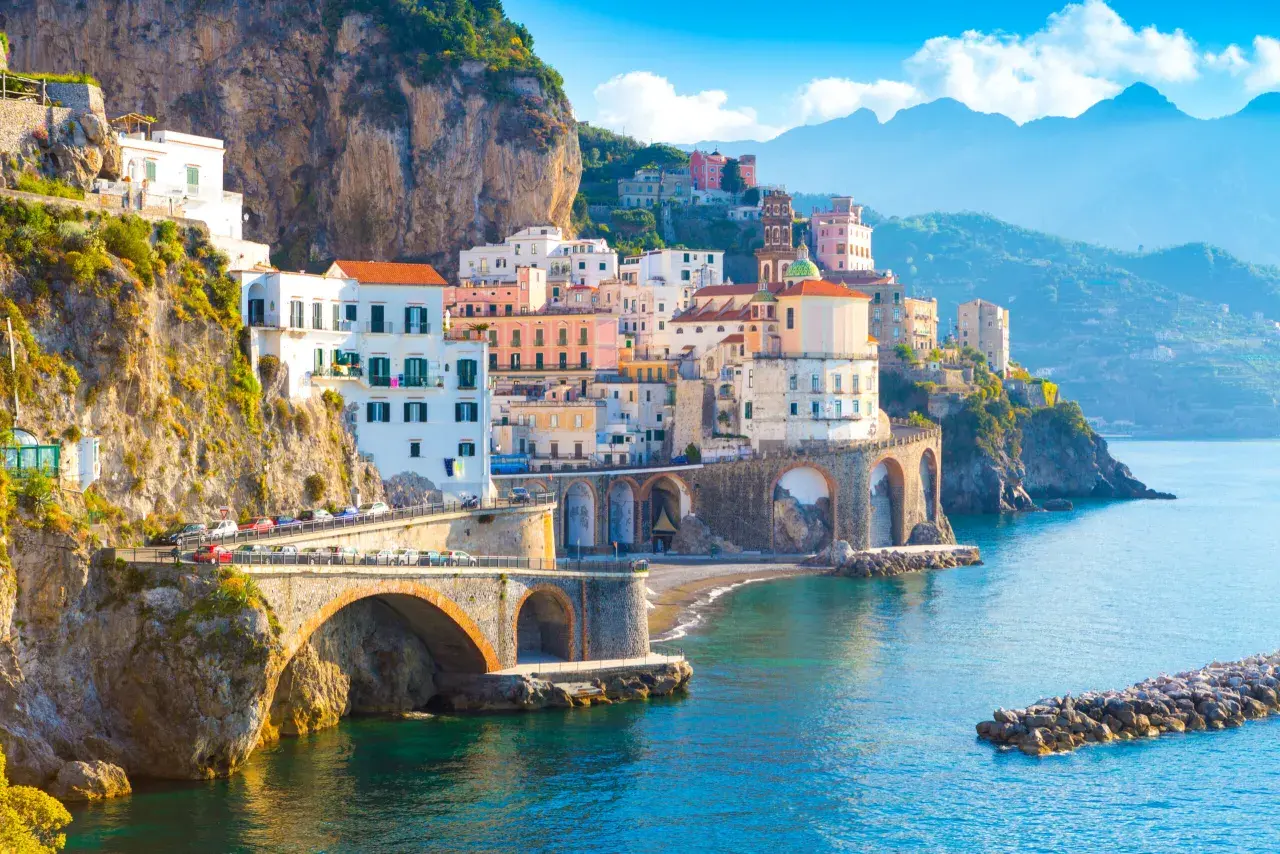 Widok na wybrzeże Amalfi z kolorowymi domami na klifie i mostem. Nawet przy takich widokach, objawy lęku przed ekspozycją na szlakach wybrzeża Amalfi a wyspa Capri mogą być odczuwalne.