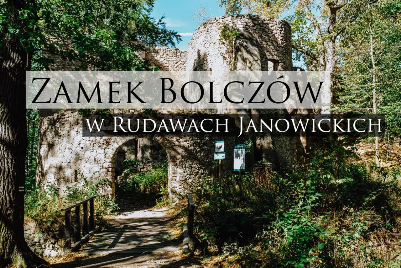 Kamienne ruiny zamku Bolczów w Rudawach Janowickich, porośnięte zielenią, z łukowym wejściem i drewnianym mostkiem.