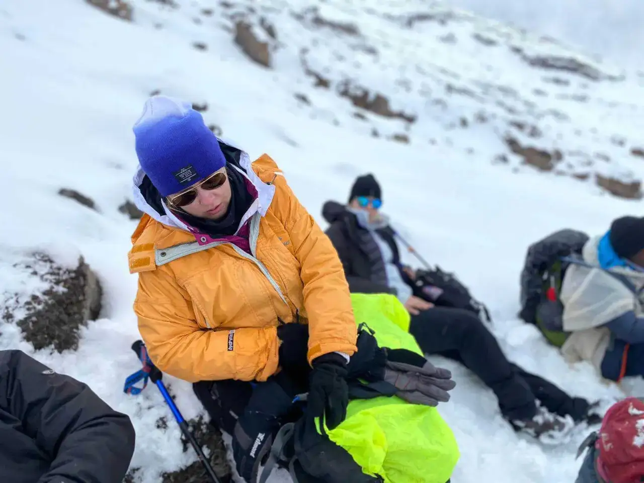Zmęczeni alpiniści odpoczywają na śniegu. Widoczne skutki braku aklimatyzacji podczas szybkiego ataku szczytowego.