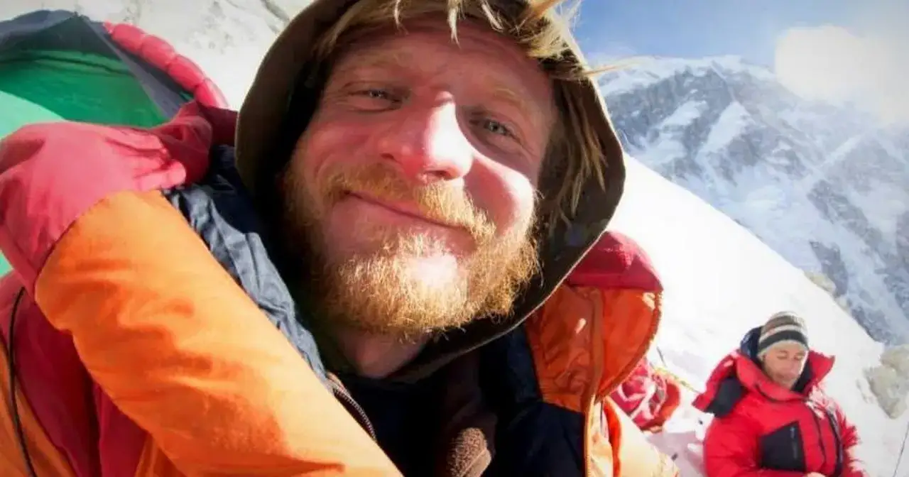 Zmęczony alpinista z zarostem na tle ośnieżonych gór. Szybki atak szczytowy bez aklimatyzacji to ogromne ryzyko.