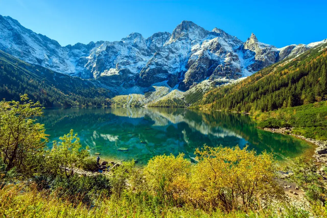 Piękne Morskie Oko, idealne na górską trasę. Woda lśni, a szczyty górskie pokryte śniegiem odbijają się w tafli jeziora.