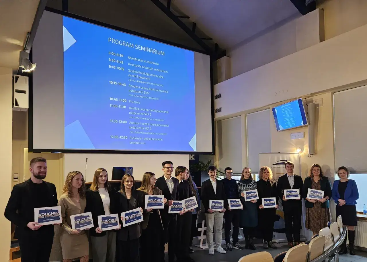 Uczestnicy seminarium z voucherami, jak dobrać tempo marszu do najsłabszego uczestnika wyprawy, stoją przed ekranem z programem.