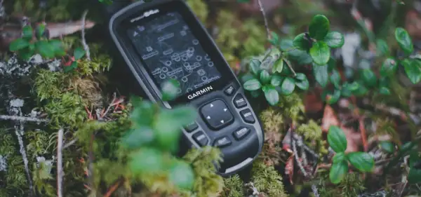 Garmin inReach, jako akcesoria do komunikacji satelitarnej, leży na mchu w lesie.